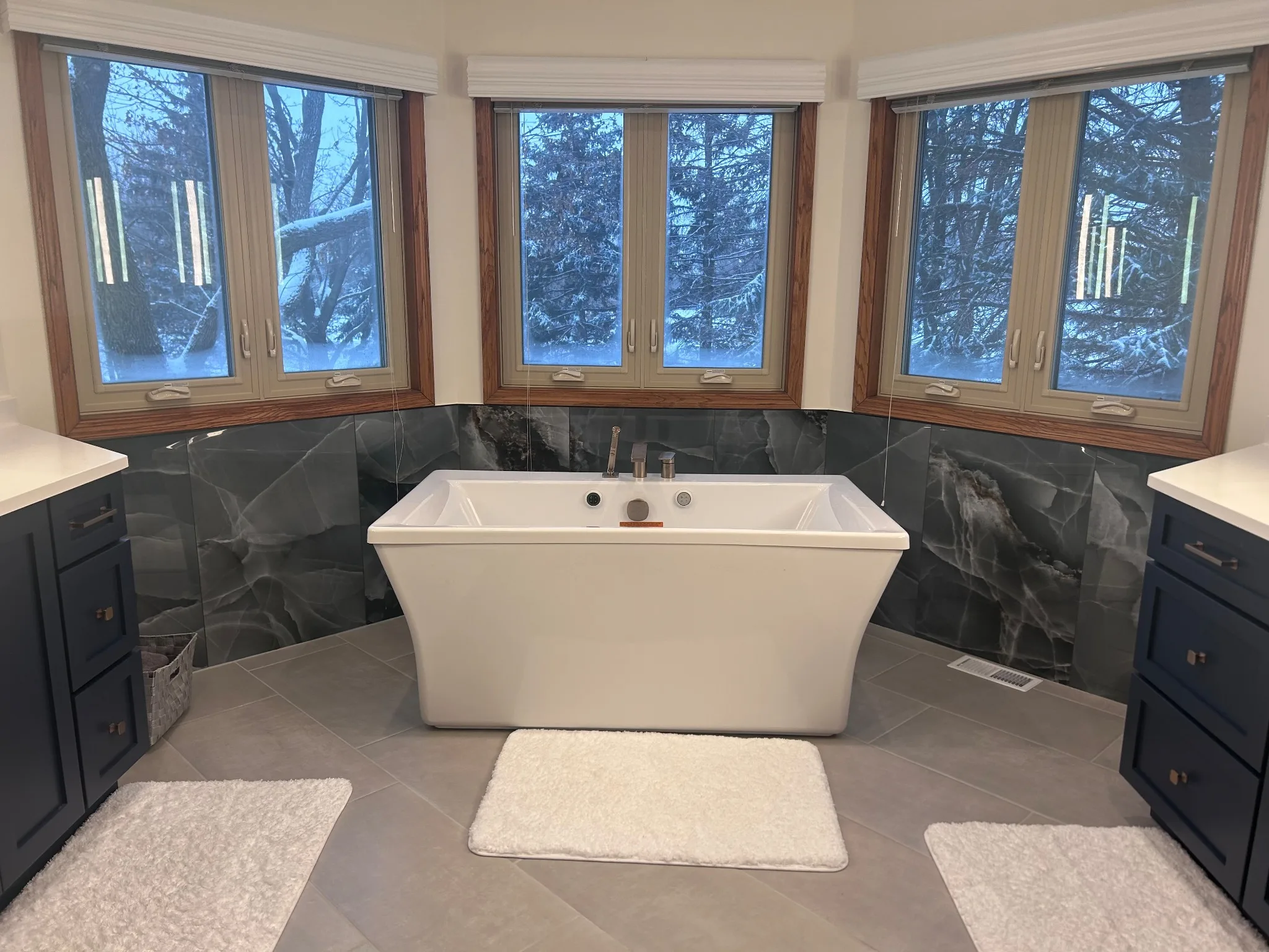 Kildeer bathroom remodel with a freestanding tub below three windows, navy vanities on both sides and large-format dark tile