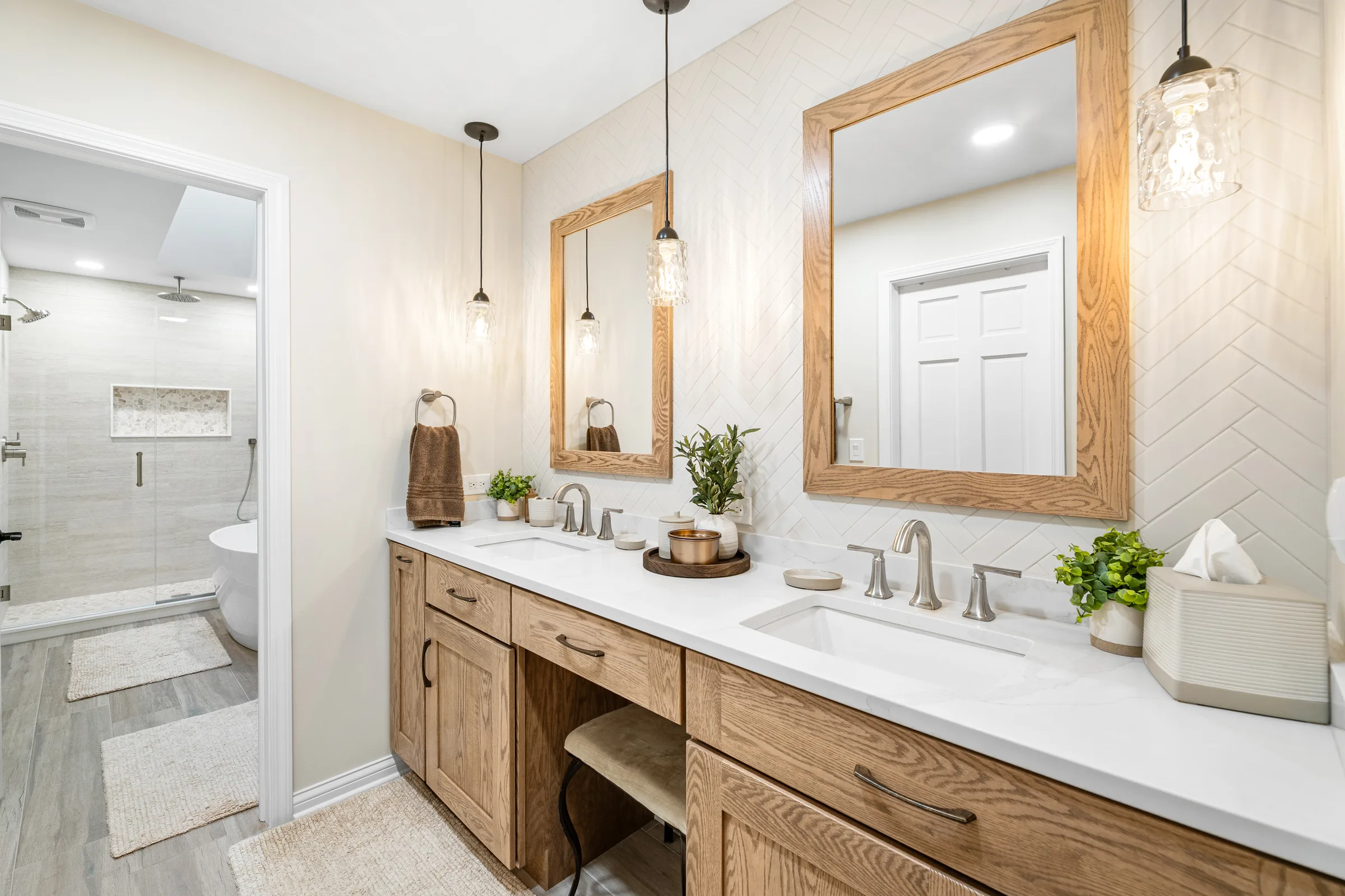 Lake Zurich primary bathroom: warm oak double vanity with herringbone accent and frameless glass shower