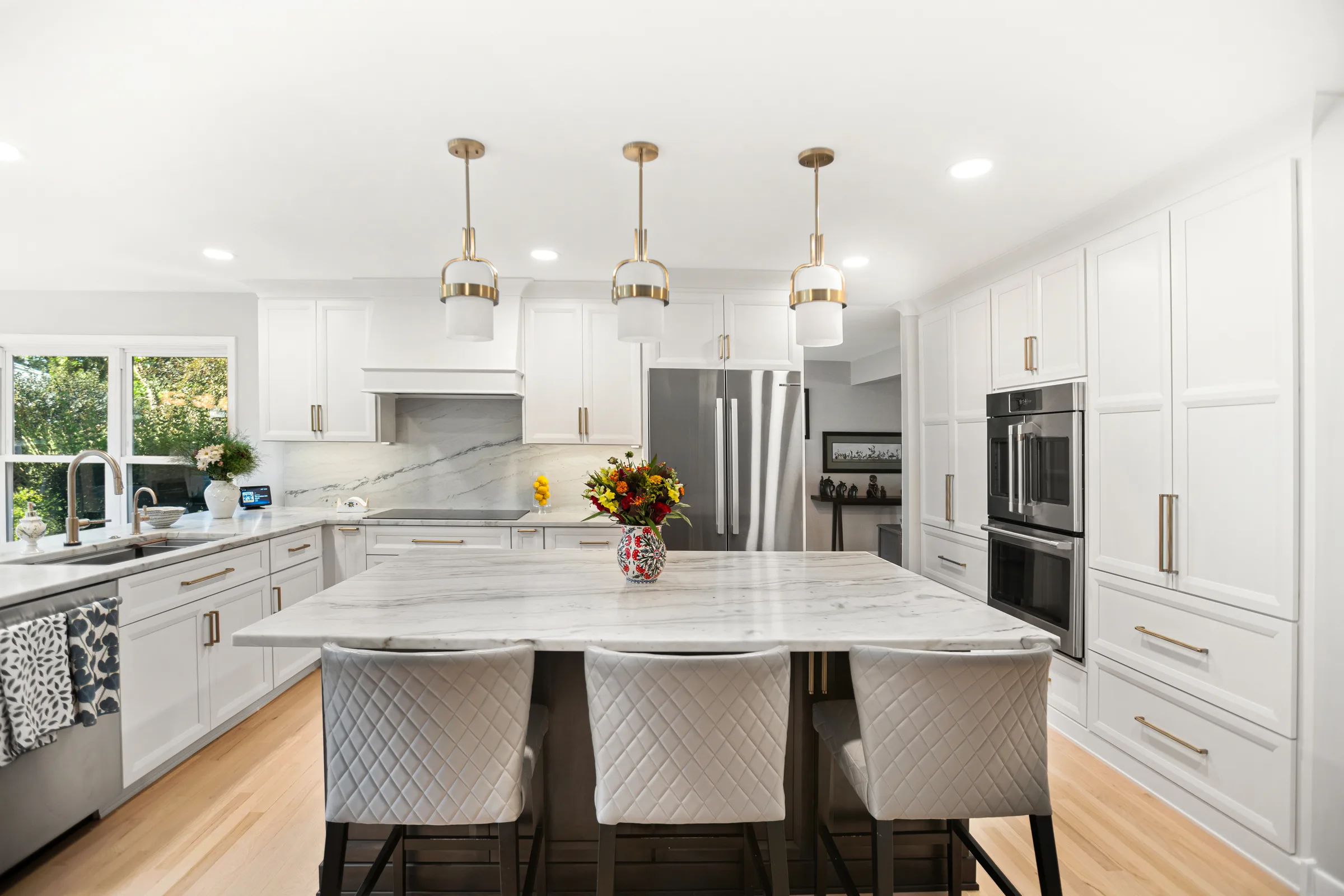 Glenview kitchen by Delta Remodels: marble island with brass pendants